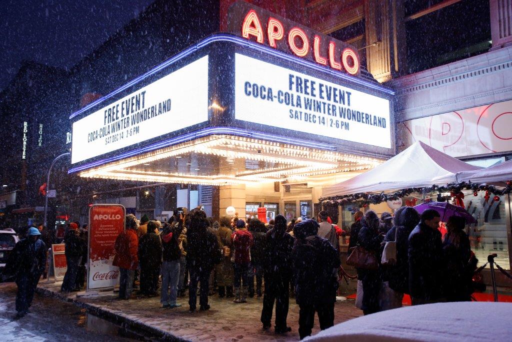 A crowd gathering in front of the Apollo Theatre in the winter time 