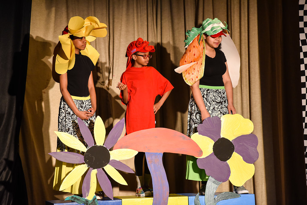 Children on stage in costumes performing a play